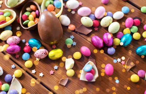 Schokoladeneier und Bonbons auf Holztisch lizenzfreie Stockfotos