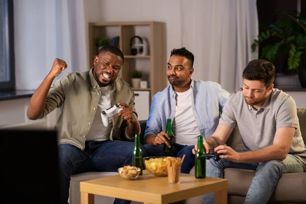 Amigos felizes jogando videogames em casa à noite — Fotografia de Stock