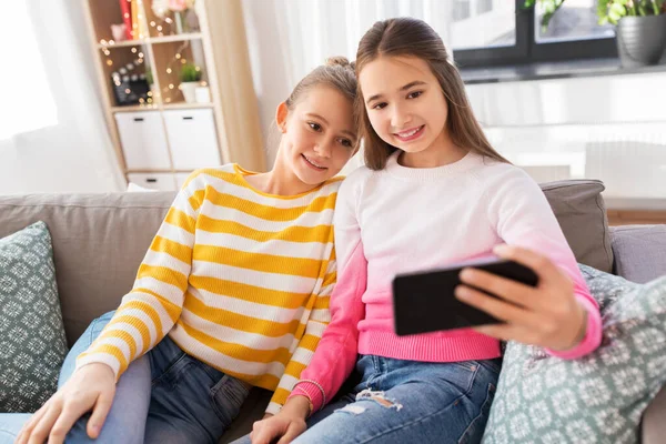 Mutlu kızlar evde akıllı telefonlarıyla selfie çekiyorlar. — Stok fotoğraf