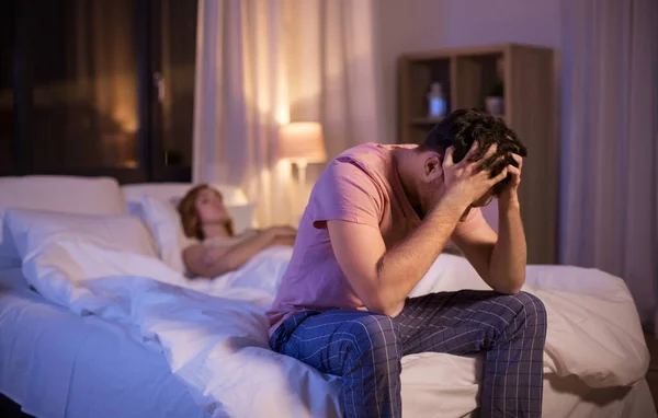 Sad man with insomnia sitting on bed at night — Stok fotoğraf