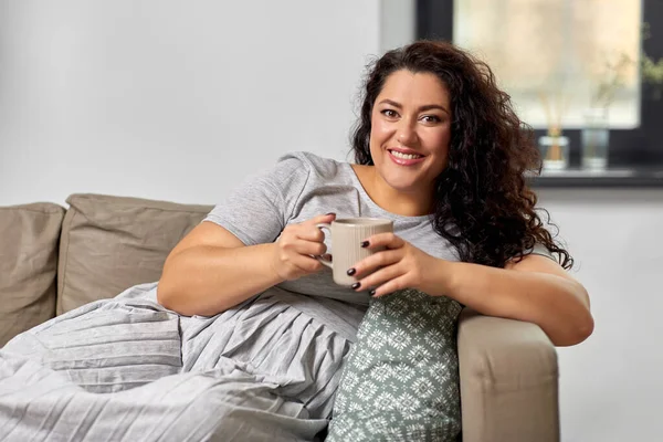 Mujer feliz bebiendo café o té en el sofá en casa — Foto de Stock