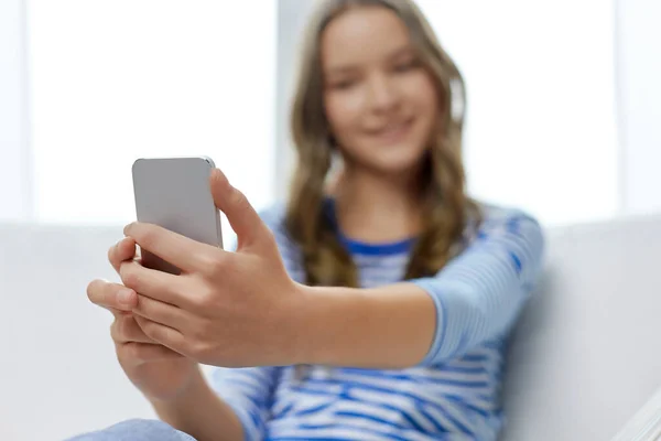 Uśmiechnięta nastolatka za pomocą smartfona w domu — Zdjęcie stockowe