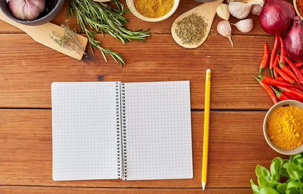 Notebook com lápis entre especiarias na mesa de madeira — Fotografia de Stock