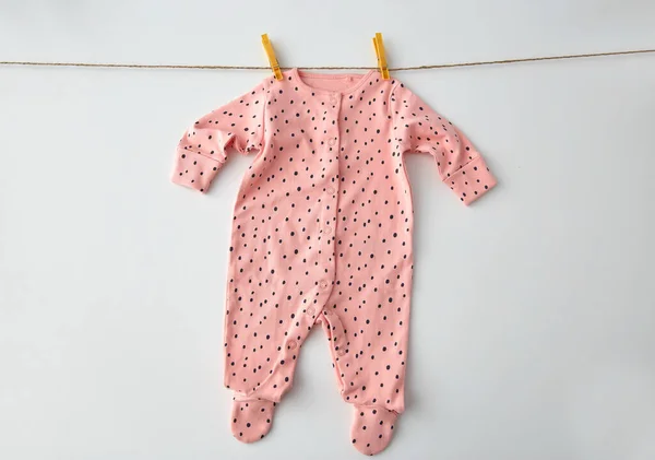 Bodysuit para bebê menina pendurada na corda com pinos — Fotografia de Stock