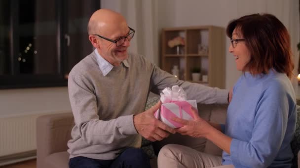 Feliz pareja de ancianos con caja de regalo en casa — Vídeos de Stock