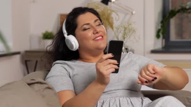 Женщина в наушниках слушает музыку на смартфоне — стоковое видео