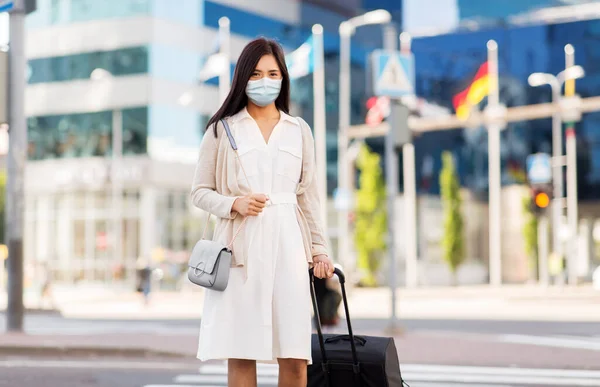 Asian woman with travel bag in protective mask — Stockfoto