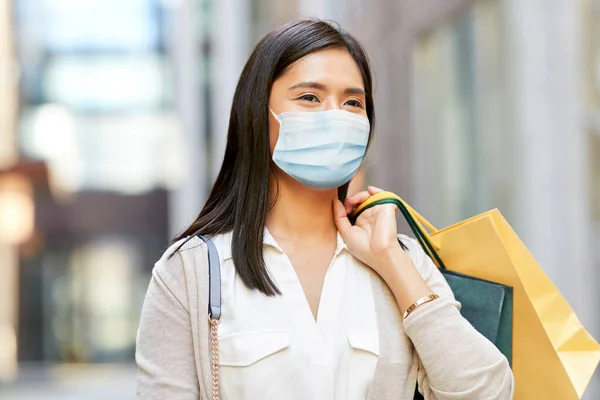 Азиатка в защитной маске с пакетами для покупок — стоковое фото