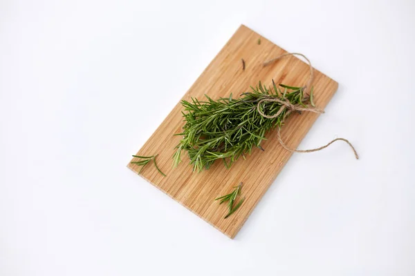 Bunch of rosemary on wooden cutting board — Stockfoto