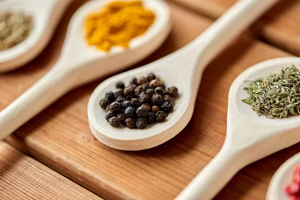 Löffel mit verschiedenen Gewürzen auf Holztisch — Stockfoto