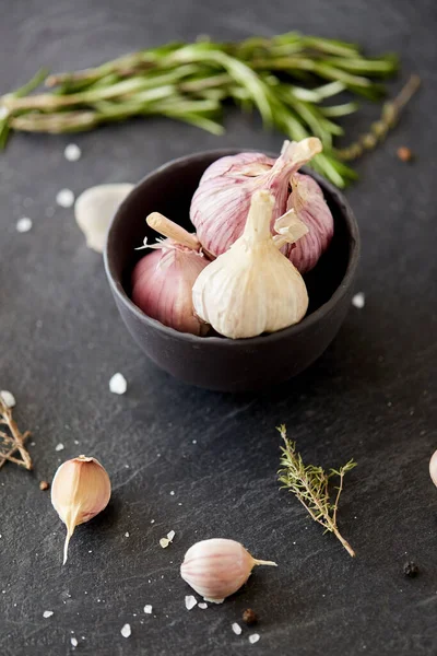 Garlic in bowl and rosemary on stone surface — Zdjęcie stockowe