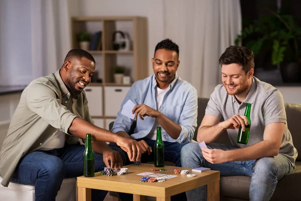 Glückliche männliche Freunde, die nachts zu Hause Karten spielen — Stockfoto
