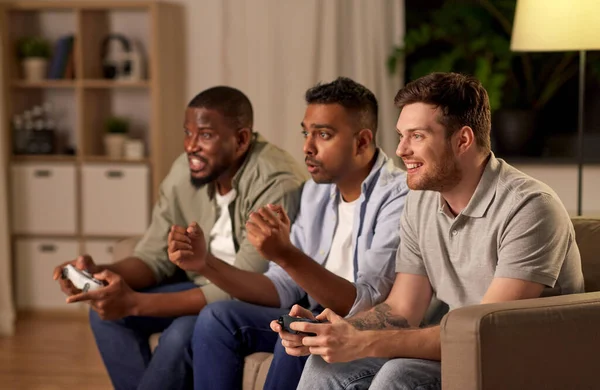 Ευτυχείς φίλοι που παίζουν βιντεοπαιχνίδια στο σπίτι τη νύχτα — Φωτογραφία Αρχείου