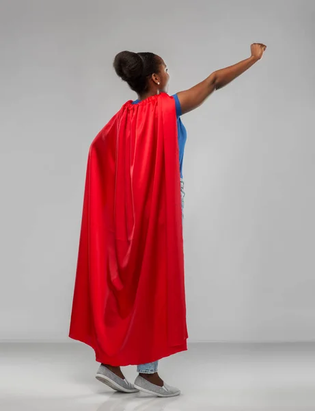 Happy african american woman in red superhero cape — Stok Foto