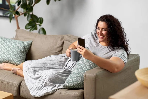 Mulher com smartphone beber café em casa — Fotografia de Stock