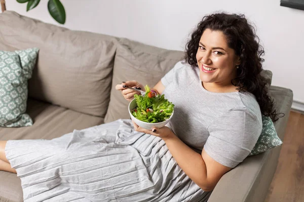 Gülümseyen genç kadın evde sebze salatası yiyor. — Stok fotoğraf