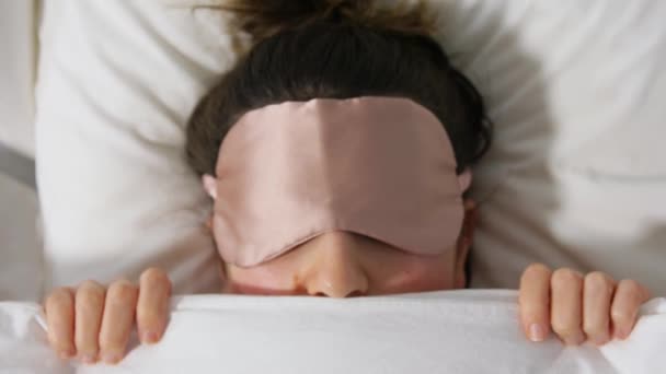 Vrouw met oog slaapmasker in bed onder deken — Stockvideo