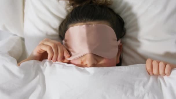 Žena s oční maskou na spaní v posteli pod dekou — Stock video