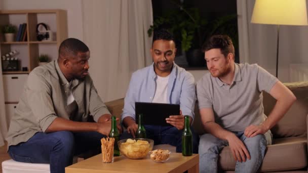 Чоловіки друзі з планшетним ПК п'ють пиво вдома — стокове відео