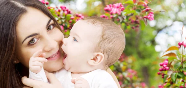 Moeder met baby over lente tuin achtergrond — Stockfoto