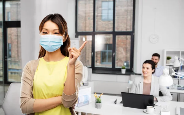 Asiatin in medizinischer Schutzmaske im Büro — Stockfoto