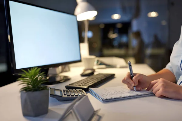 Business woman writing to notebook at night office — стоковое фото