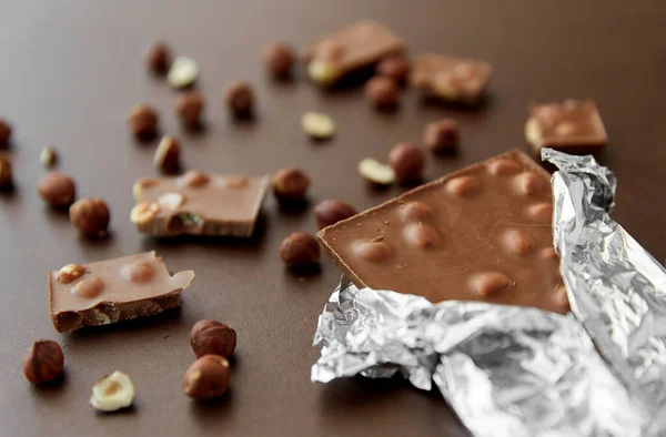 Milk chocolate bar with hazelnuts in foil wrapper — Stock Photo, Image