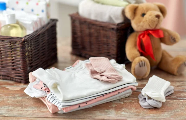Детская одежда и игрушка плюшевого мишки на столе дома — стоковое фото