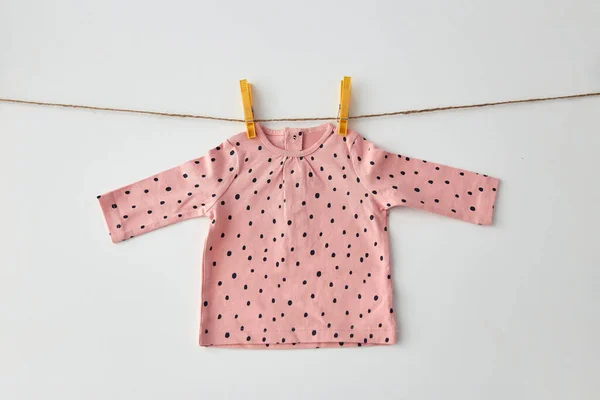 Rosafarbenes Hemd für Baby-Mädchen, das an einem Seil mit Nadeln hängt — Stockfoto