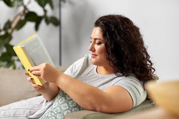 Jovem mulher ler livro no sofá em casa — Fotografia de Stock