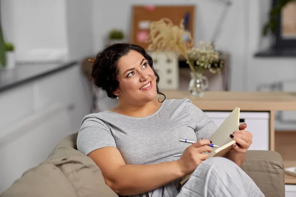 Glad ung kvinna med dagbok på soffan hemma — Stockfoto