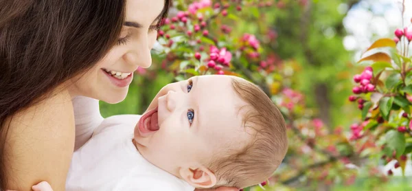 Madre con bebé sobre fondo de jardín de primavera —  Fotos de Stock