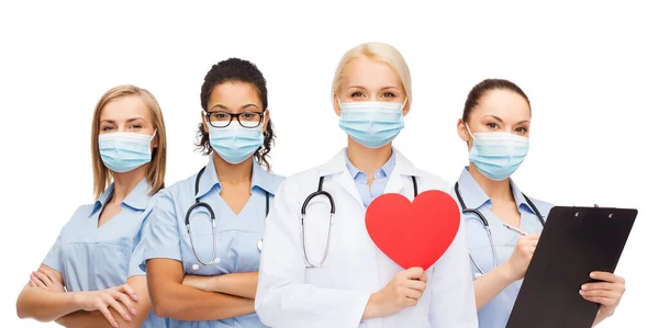 Médicos em máscaras médicas protetoras com coração vermelho — Fotografia de Stock