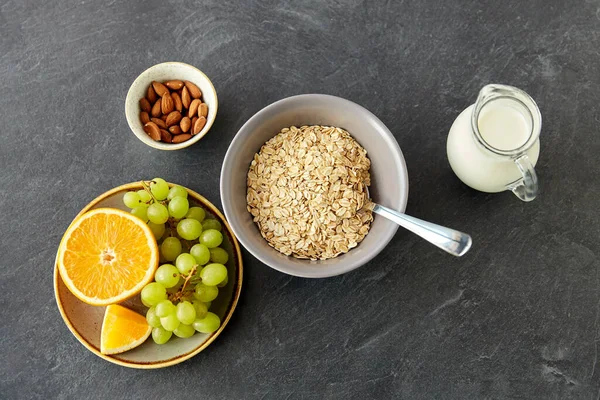 Oatmeal with fruits, almond nuts and jug of milk — Stockfoto