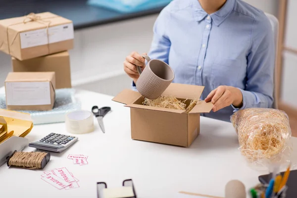 Žena balení hrnek na balíček box na poště — Stock fotografie