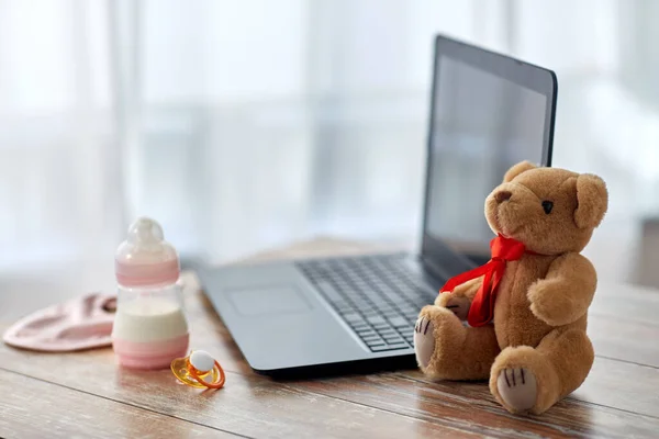 Baby milk formula, laptop, soother and teddy bear — Stock Photo, Image
