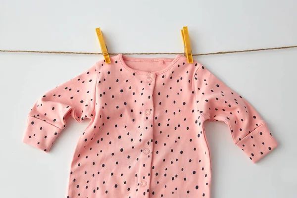 Bodysuit para bebê menina pendurada na corda com pinos — Fotografia de Stock