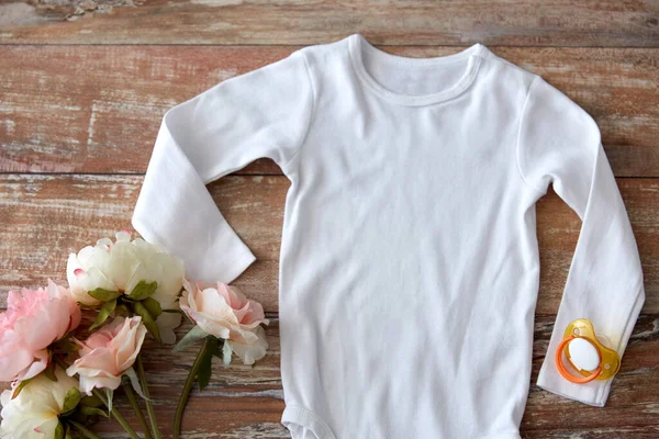 Baby bodysuit with soother and flowers on wood — 스톡 사진