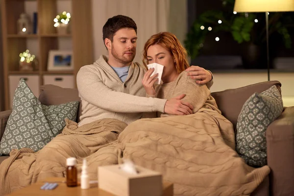 Enferma joven pareja con tejido sonándose la nariz en casa — Foto de Stock