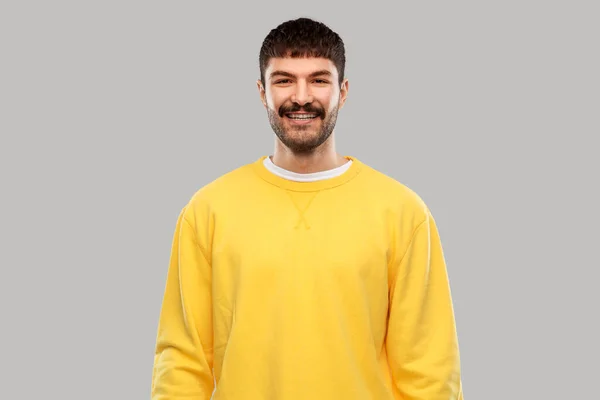 Hymyilevä nuori mies keltaisessa puserossa — kuvapankkivalokuva