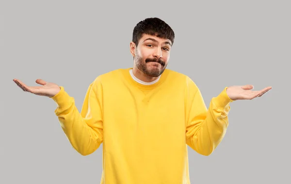 Confused man in yellow sweatshirt shrugging — 图库照片