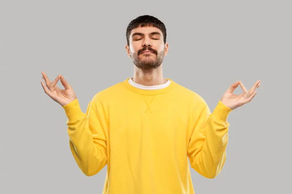 Young man in yellow sweatshirt meditating — Zdjęcie stockowe