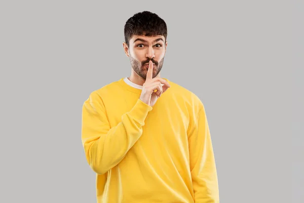 Young man making hush gesture with finger on lips — Stock Photo, Image