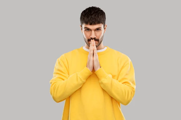 Человек в желтой толстовке молится или благодарит — стоковое фото
