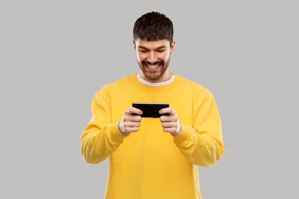 Glad leende ung man med smartphone — Stockfoto