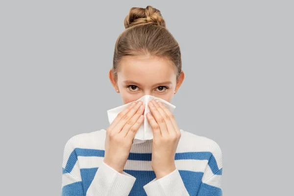 Sick teenage girl blowing nose with paper tissue — Stockfoto