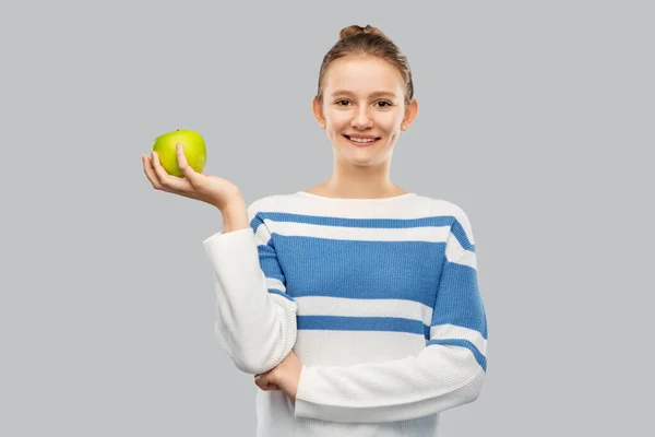 Smiling teenage girl in pullover with green apple — ストック写真