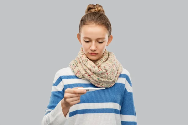 Sick teenage girl in scarf measuring temperature — Stock Photo, Image