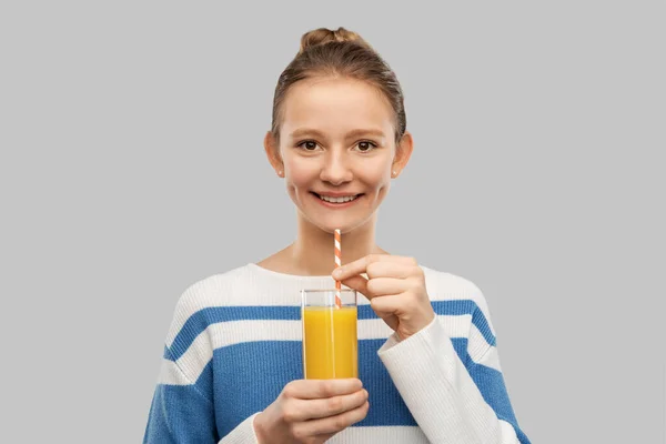 Smiling teenage girl holding glass of orange juice — Stockfoto
