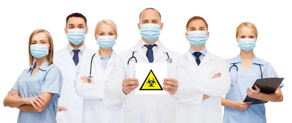 Médicos em máscaras médicas com sinal de risco biológico — Fotografia de Stock